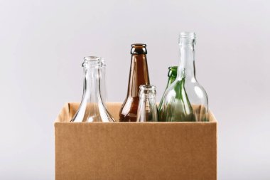 Bir karton kutunun içinde açık, yeşil ve kahverengi şişeler var.