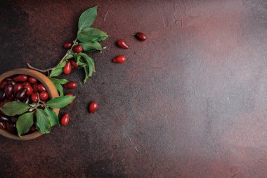 Yapraklı kirazlar ve koyu kırmızı kırsal yüzeyde ahşap kâse.