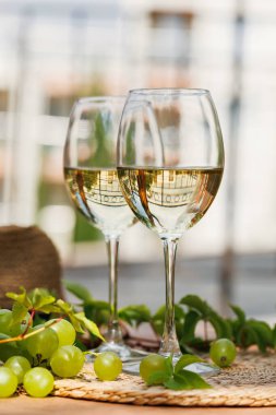 Hasır kaplamalı yeşil üzümlü beyaz şarap kadehlerini yakın plan ve arka plan