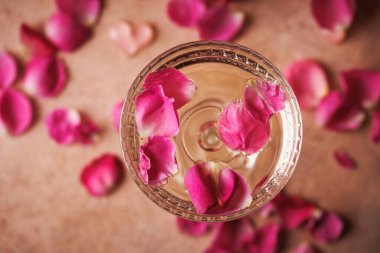 Köpüklü şarap ve narin gül yapraklarıyla dolu bir bardak neşeli bir ortam yaratıyor..