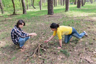 Anne ve genç oğlu bahar pikniği sırasında ormanda kamp ateşi yakmak için birlikte çalışıyorlar.