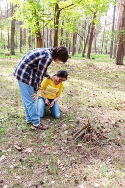 Ormandaki piknik sırasında annesinin üzerine eğilip birlikte ateş yakmışlar.