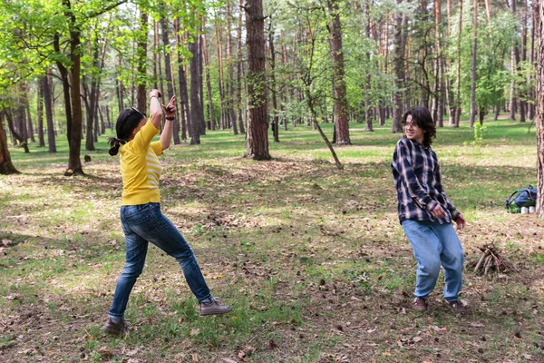 Anne ve genç oğul birlikte oynuyorlar ve ormanda gülüyorlar.