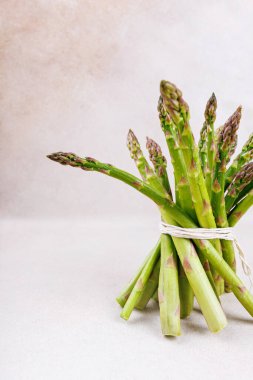 Sağlıklı yeşil kuşkonmaz, beyaz yüzeyde beyaz iplikle bağlanmış bir demet mızrakta.