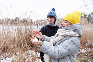 Genç bir çocuk ve annesi dışarıda karla oynuyorlar, kış manzarasında huzurlu bir yürüyüş sırasında bir kartopu tutuyorlar.