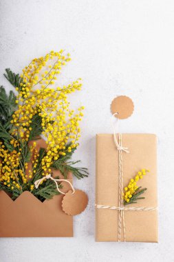 Zarfta mimoza buketi olan bahar indirimi konsepti ve açık arkaplanda boş fiyat etiketli eko paketlenmiş hediye.