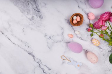 Benekli pastel Paskalya yumurtaları, şeker yumurtaları ve mermer yüzeyde pembe güller.