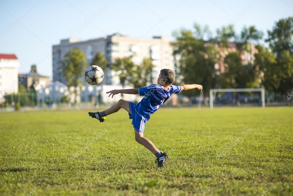 Boy kicking soccer on the footboll field