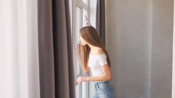Γενέθλια νεαρή γυναίκα περιμένει τους επισκέπτες κοντά στο παράθυρο. — Αρχείο Βίντεο