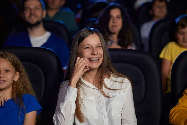 Jovencita riendo con aparatos dentales en el cine. — Foto de Stock