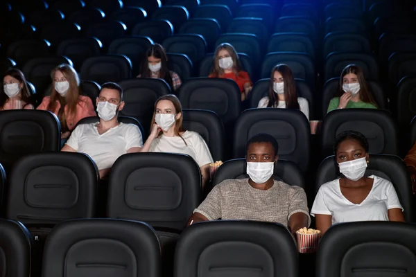 Audience wearing face masks enjoying time in cinema.