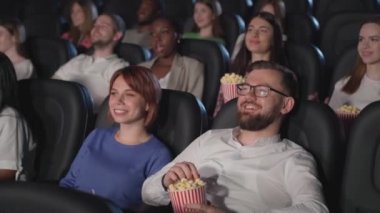 Çok ırklı genç yetişkinler sinemada komediden keyif alıyorlar..
