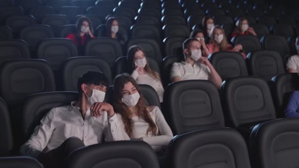 Para w maskach do twarzy rozmawiająca w kinie. — Wideo stockowe