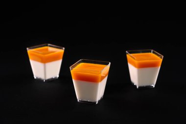 Siyah üzerine izole edilmiş panna cotta ile küçük kare camlar.