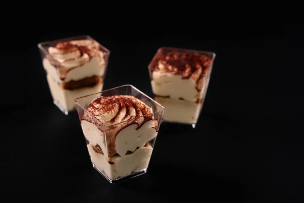 Tre bicchieri con tiramisù isolato su nero. — Foto Stock