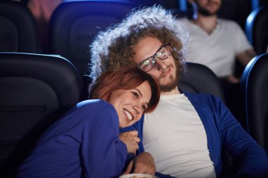 Sinemada erkek arkadaşının omzunda uzanan bir kadın..
