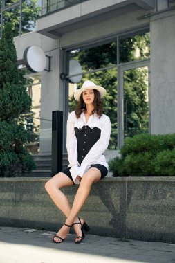 Moda modeli ofis binasının yanında oturuyor..