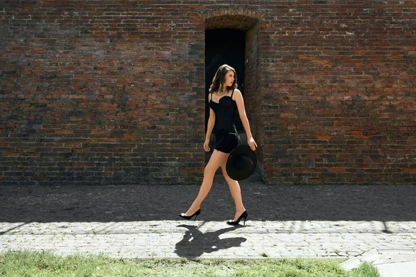 Mujer joven con vestido caminando cerca de la pared de ladrillo. —  Fotos de Stock