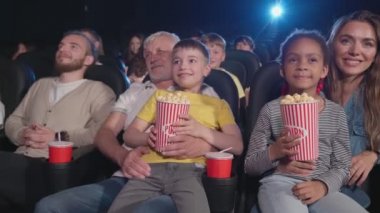 Sinemada dizlerinin üstünde çocukları olan aileler..