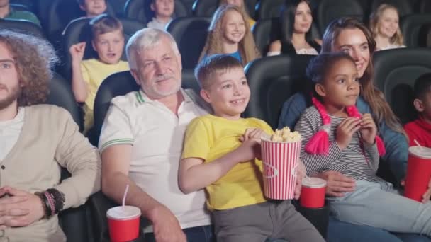 Pais com filhos de joelhos batendo palmas no cinema. — Vídeo de Stock