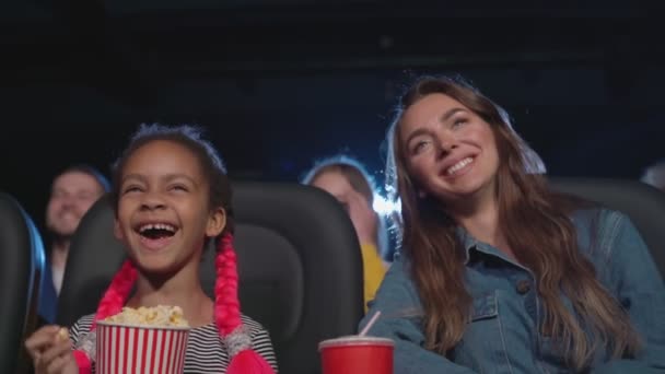 Мультирасовая семья наслаждается мультфильмом в кинозале. — стоковое видео