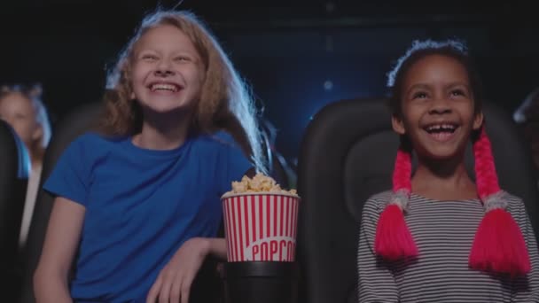 Wielorasowe dzieci korzystających śmieszne kreskówki w sali kinowej. — Wideo stockowe