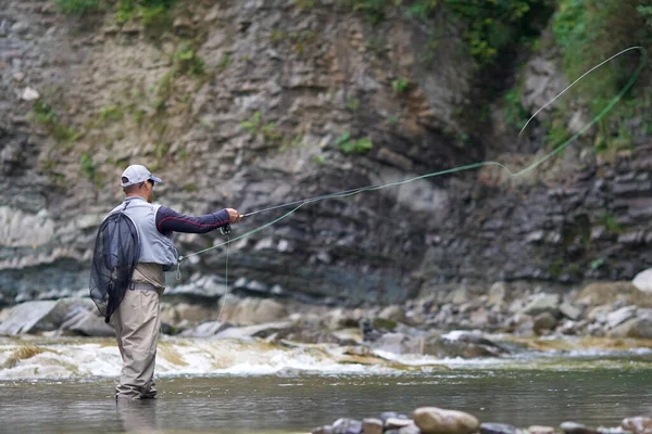 Professionele visser gooien staaf in ruwe rivier — Stockfoto