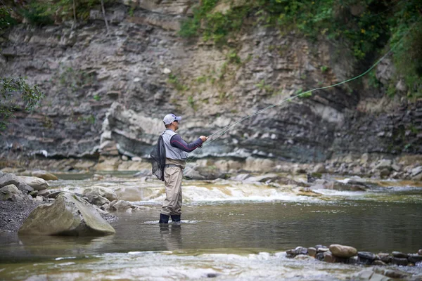 Bevoegde visser haken met staaf in ruwe rivier — Stockfoto