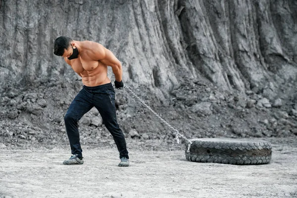 Muskulös man i mask tränar utomhus med däck — Stockfoto