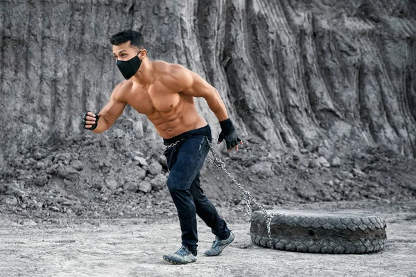 Мускулистый парень тянет тяжелые шины во время тренировок на открытом воздухе — стоковое фото