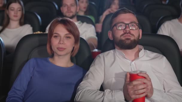 Смеющаяся пара смотрит фильм ужасов в кино. — стоковое видео