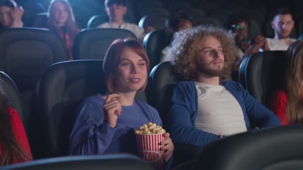 Multiraciala människor tittar på tråkig film på bio. — Stockvideo