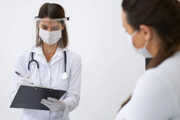 Doctor in het gezicht masker voor de behandeling van zwangere vrouw — Stockfoto