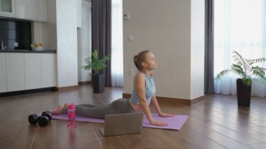 Dizüstü bilgisayarda video izlerken kadın uzanıyor.