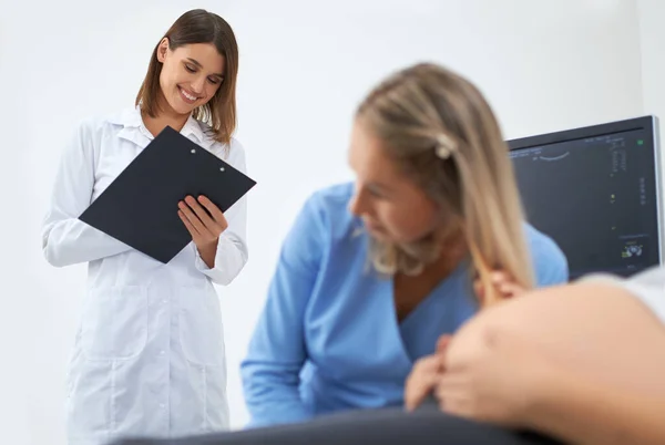 Médecin et assistant examinant une femme enceinte à la clinique — Photo