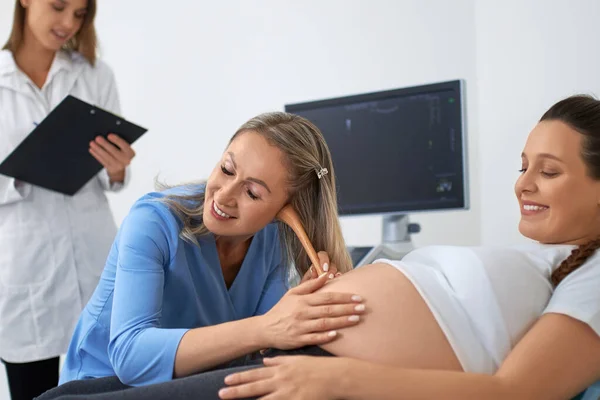Médico escuchando barriga de mujer embarazada — Foto de Stock