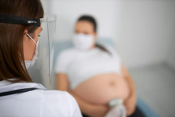Arzt in Maske macht Ultraschalluntersuchung für Schwangere — Stockfoto