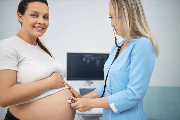 Pregnant woman getting medical treatment by female doctor — Fotografia de Stock