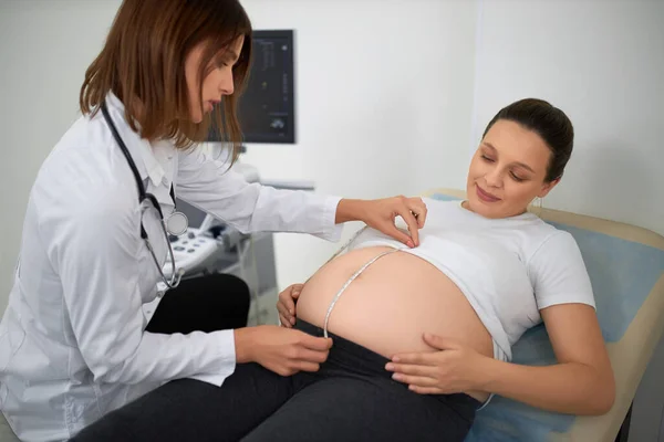 Gynécologue mesure avec du ruban adhésif ventre de la femme enceinte — Photo
