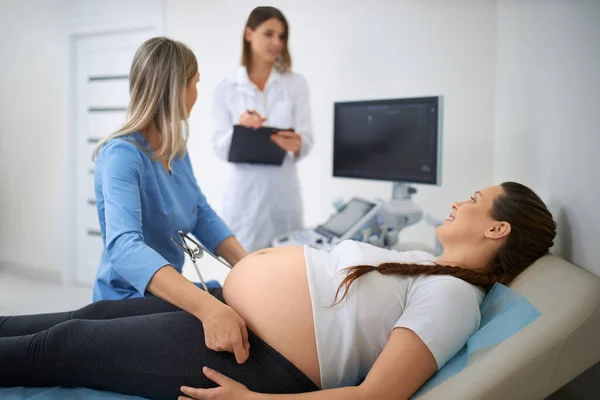 Qualified gynecologist taking measurement of pregnant woman