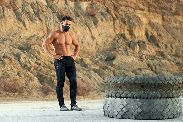 Tipo musculoso en máscara negra haciendo ejercicio con neumáticos al aire libre — Foto de Stock