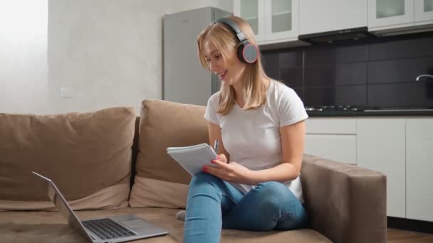 Kobieta w słuchawkach o kursy online na laptopie — Wideo stockowe