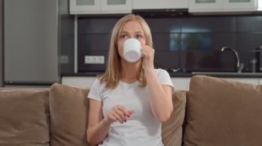 Hoş bir kadın televizyon seyrediyor ve çay içiyor.