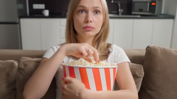 Aufgeregte Frau schaut Film und isst Popcorn — Stockvideo