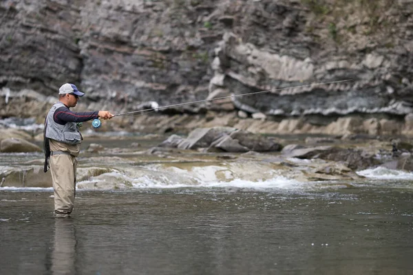 Hombre relajado en ropa impermeable pesca en el río — Foto de Stock