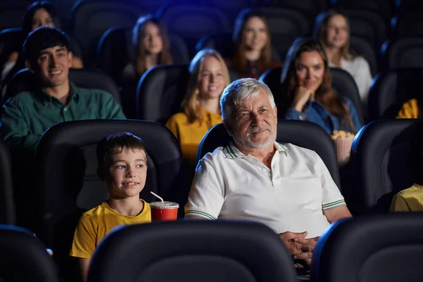 Nagyapa unoka élvezi rajzfilm moziteremben. — Stock Fotó