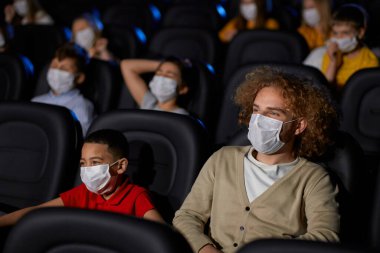 Sinemada yüz maskesi takan çok ırklı bir aile..