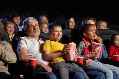 Sinemada dizlerinde küçük çocuklar olan insanlar..