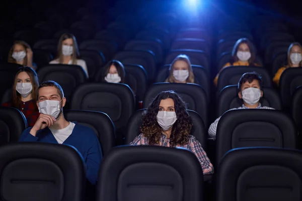 Young audience wearing face masks in cinema.