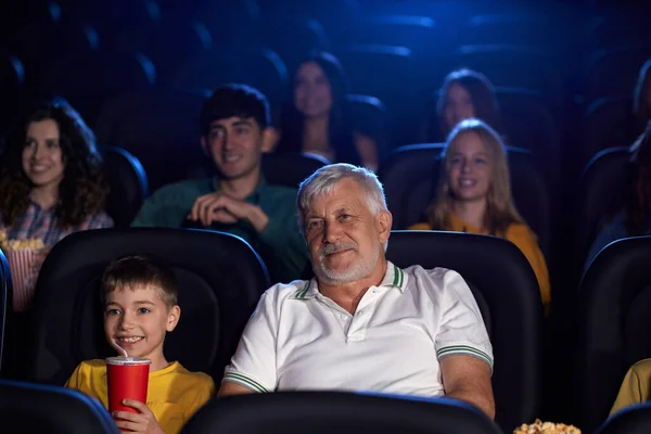 Дедушка с внуком наслаждается мультфильмом в кинозале. — стоковое фото